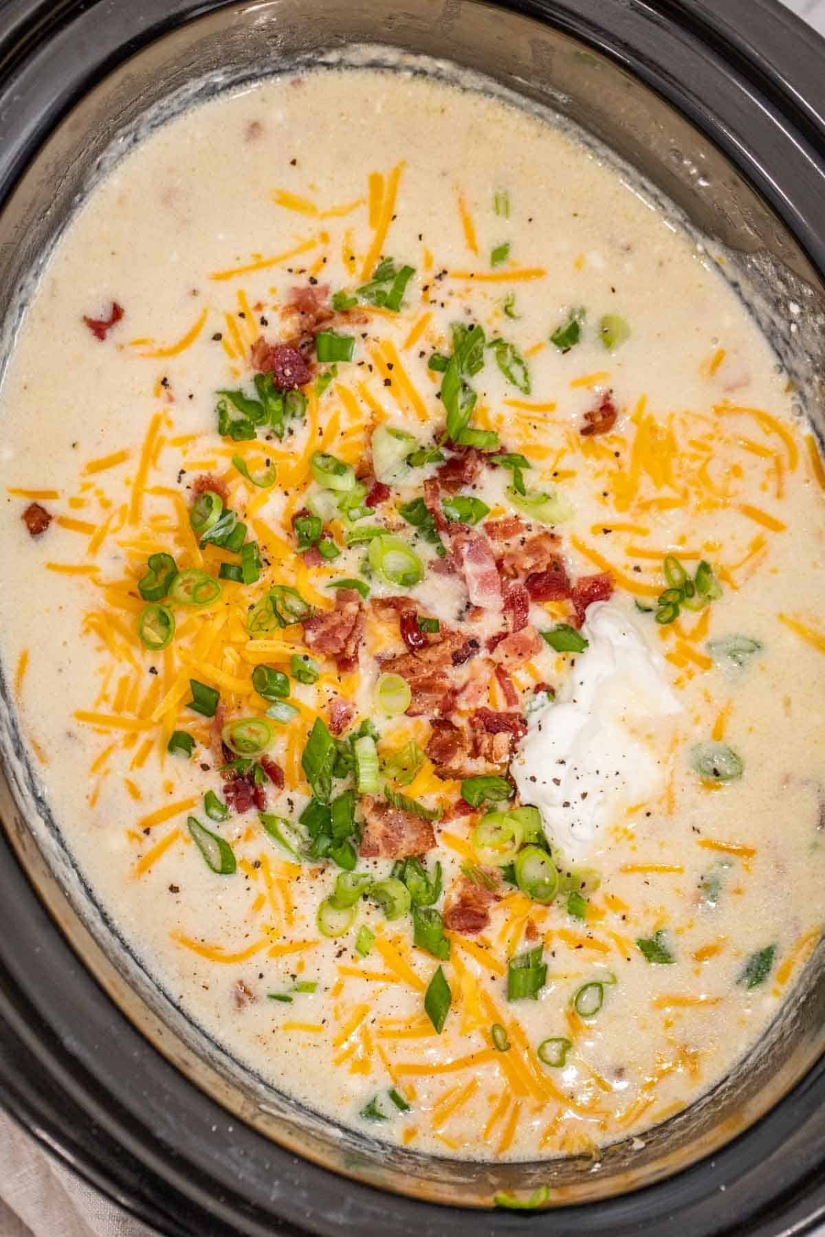The finished potato soup topped with bacon, cheese, green onions, and sour cream.