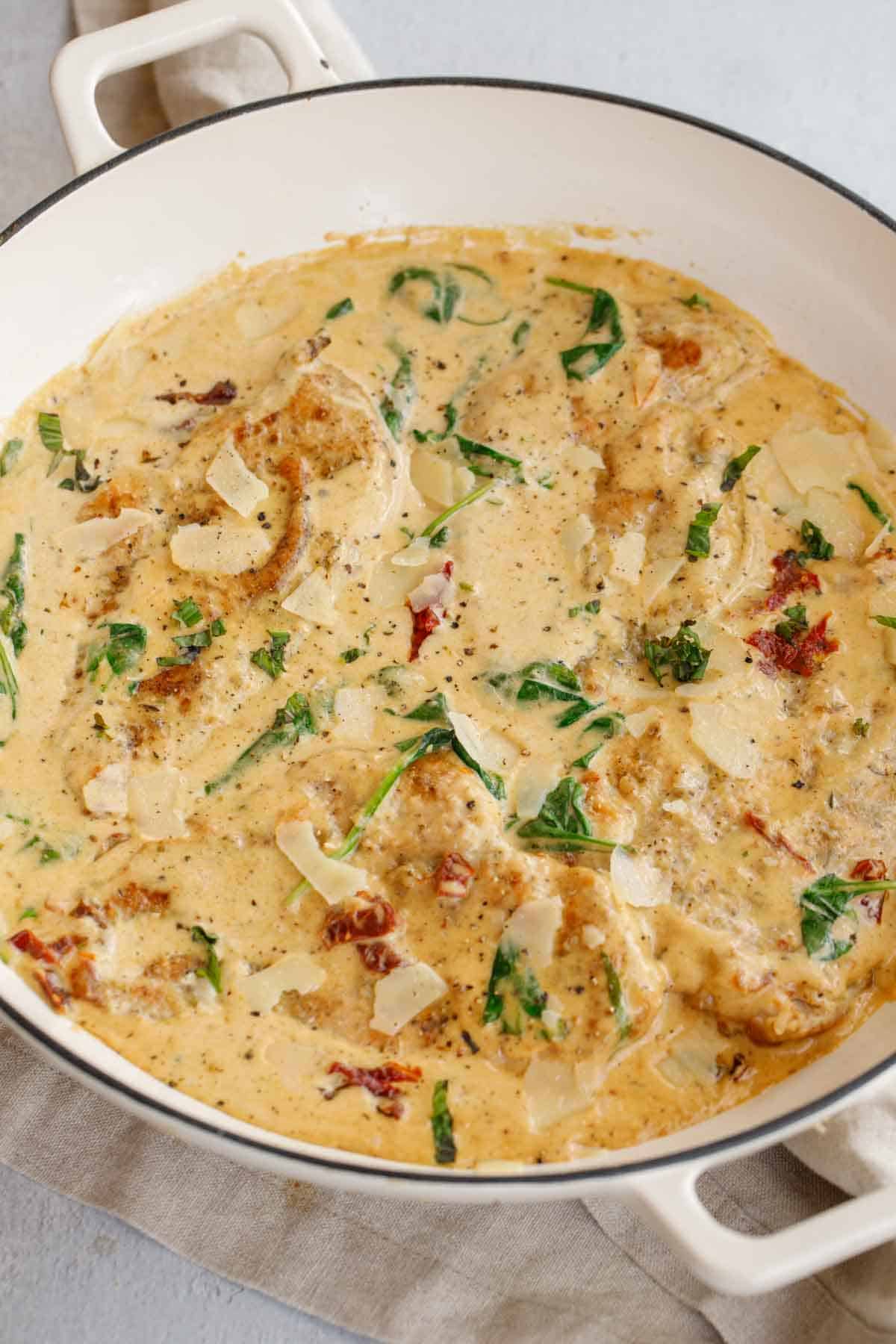 A white pot of creamy tuscan chicken.