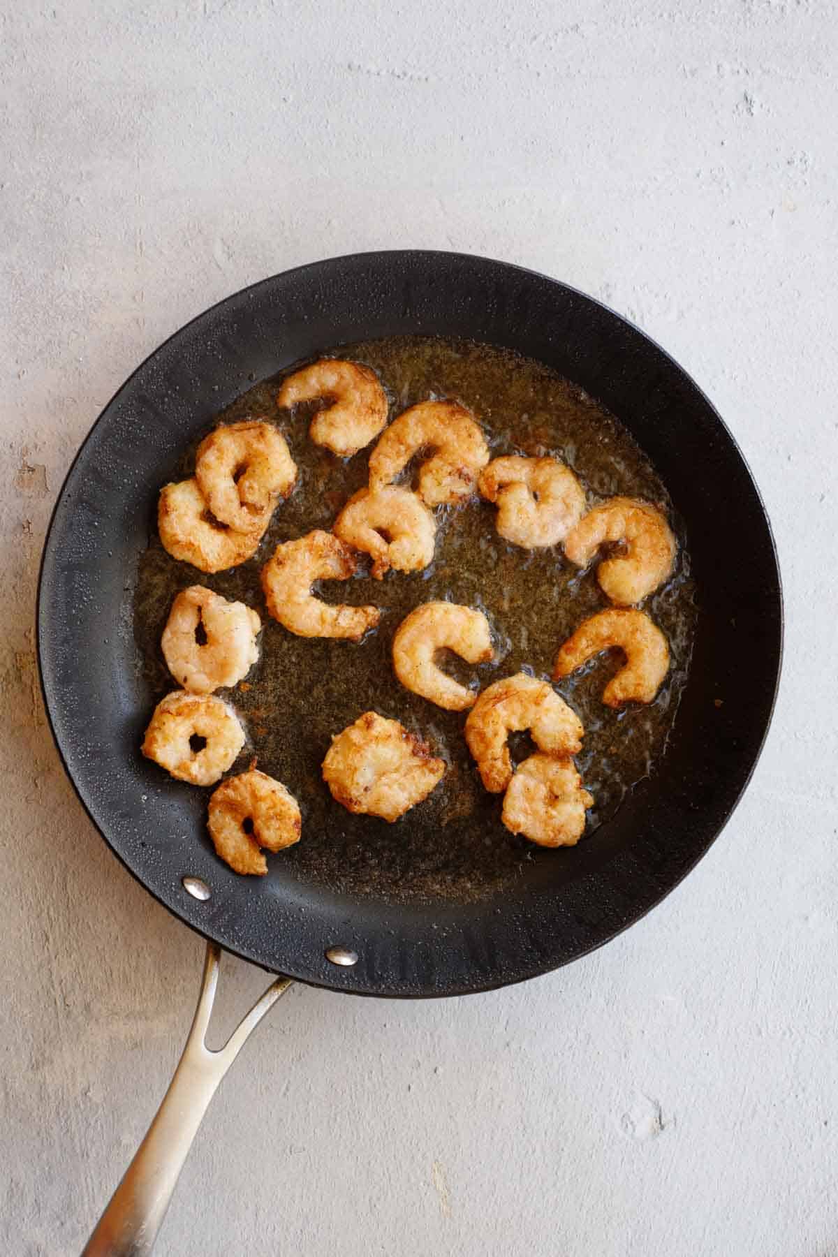 The shrimp cooking in a frying pan.