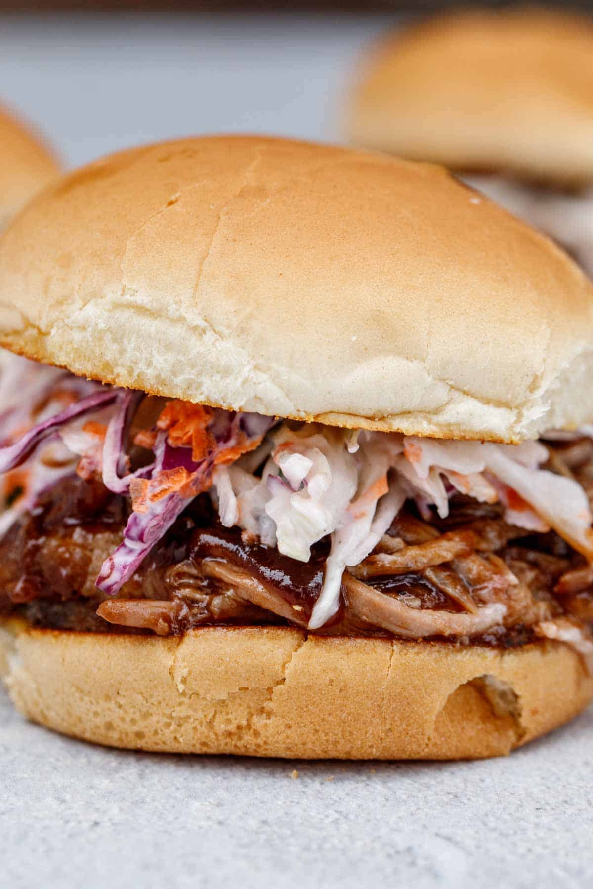A pulled pork sandwich topped with coleslaw. 