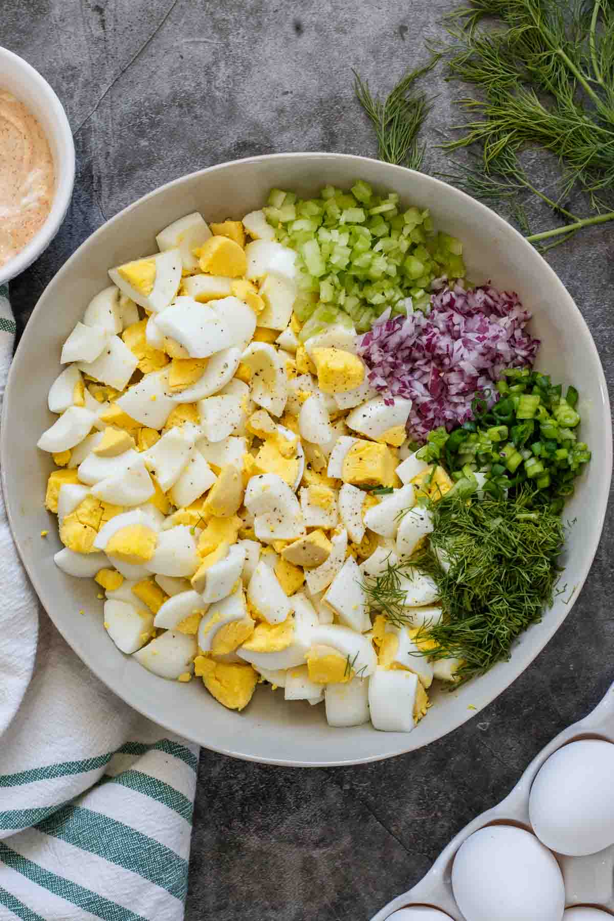 Egg salad ingredients in a gray bowl unmixed. 