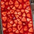 A glass baking pan with the jello in it, topped with sliced strawberries.