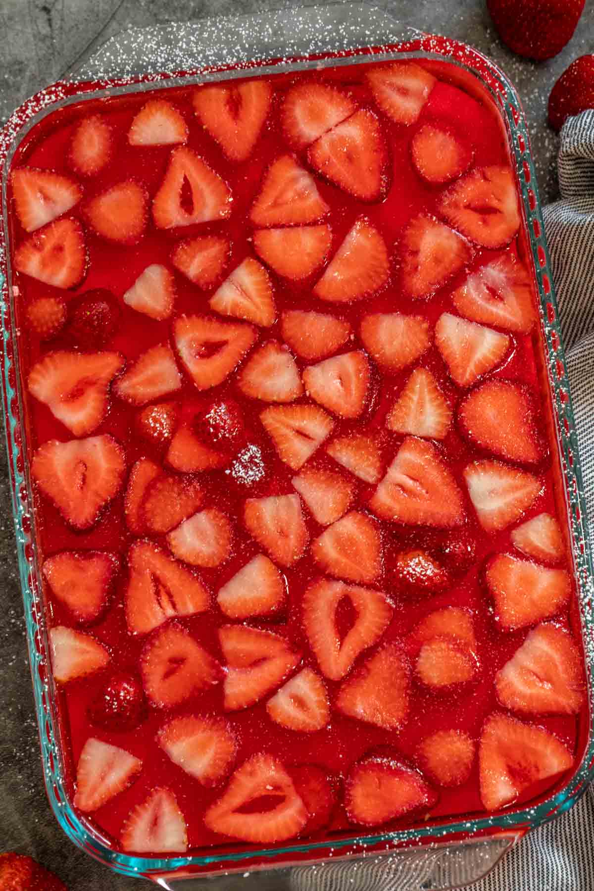 A glass baking pan with the jello in it, topped with sliced strawberries. 