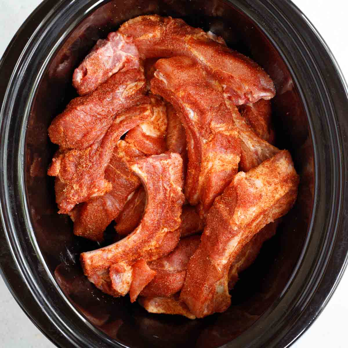 The pork ribs in a crockpot ready to be cooked.