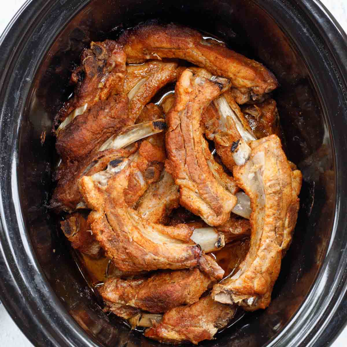 The cooked ribs in the crockpot.