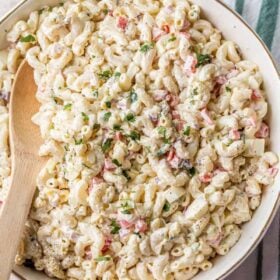 A pot of macaroni salad with a wooden spoon in it.