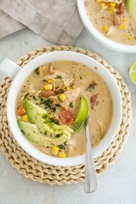A white bowl of white chicken chili with toppings.