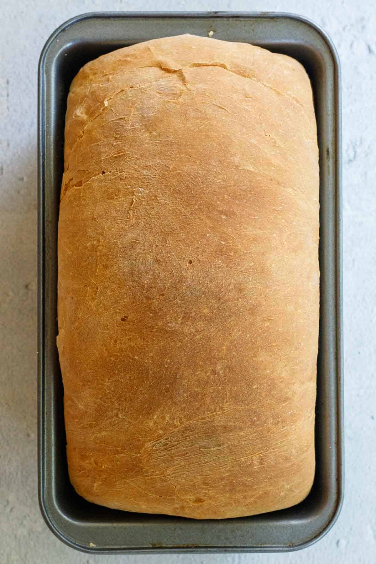 A loaf pan with the baked bread in it.