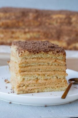 A slice of dulce de leche cake on a white plate.
