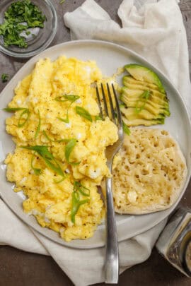 A plate of cottage cheese with avocado and an englsh muffin.