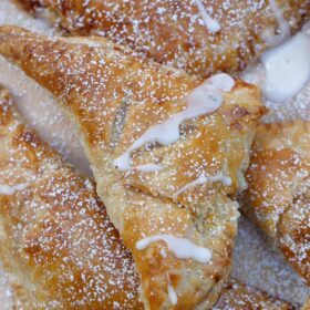 Crispy baked apple turnovers, topped with powdered sugar and a glaze.
