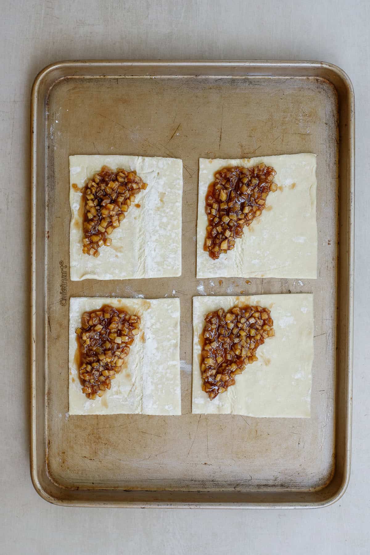 This quick and easy apple turnover recipe is a fall dessert that cooks with just a few ingredients. 3 squares of puff pastry dough with a spoonful of apple filling in each corner.