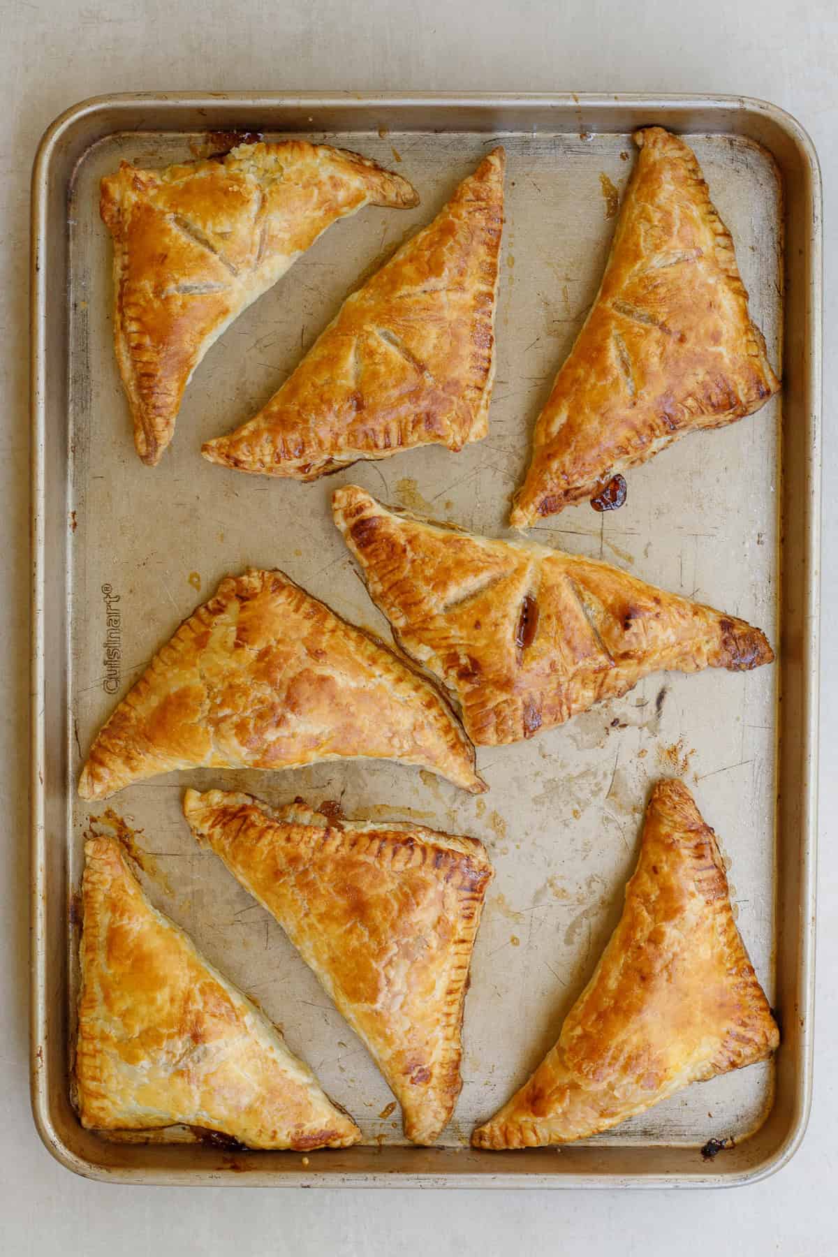 This quick and easy apple turnover recipe makes the perfect fall pastry with apples. A baking sheet with the baked turnovers.