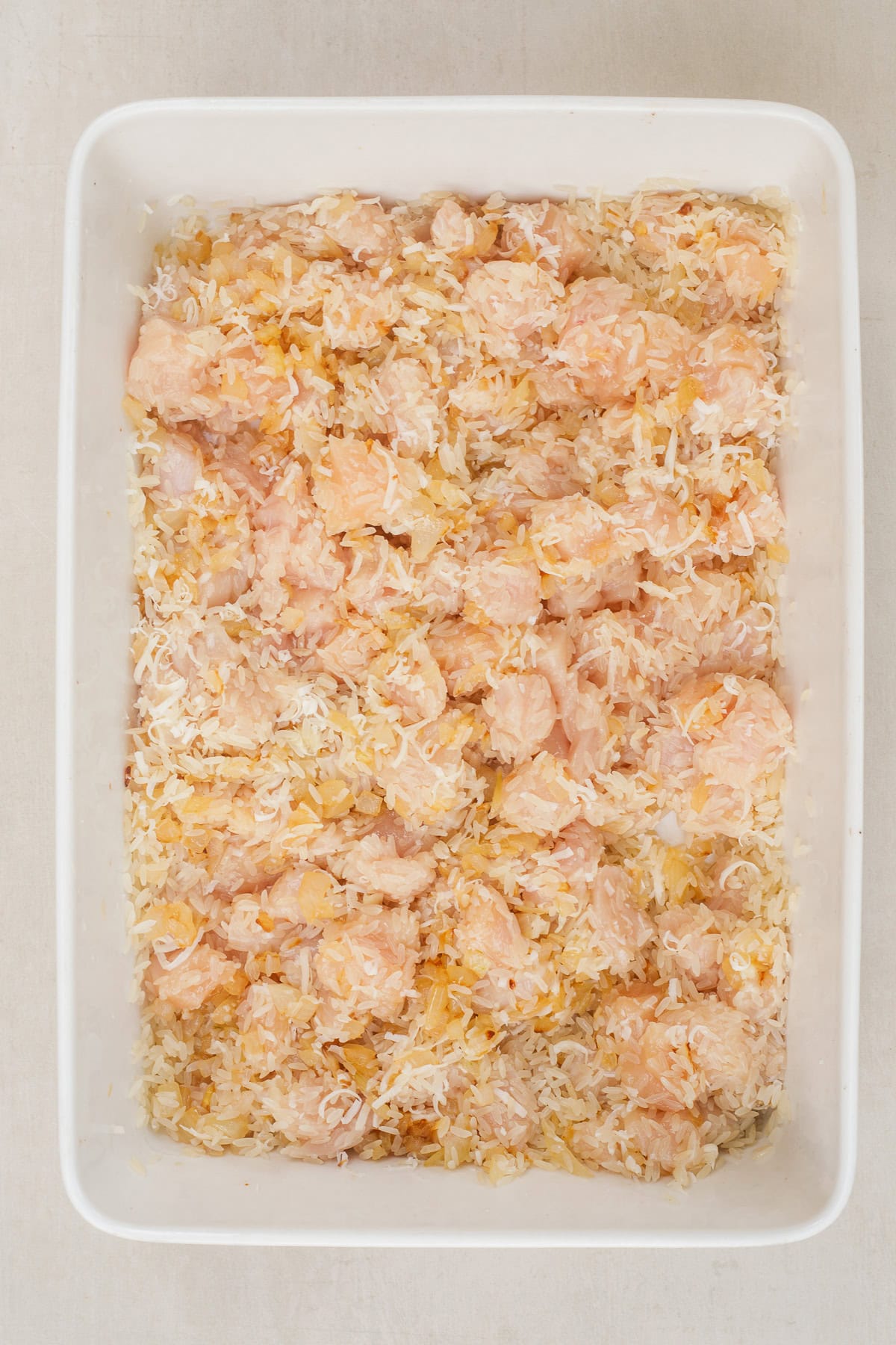 Our homemade chicken and rice casserole recipe is the perfect easy and delicious comfort meal. A casserole dish with the raw chicken and rice.
