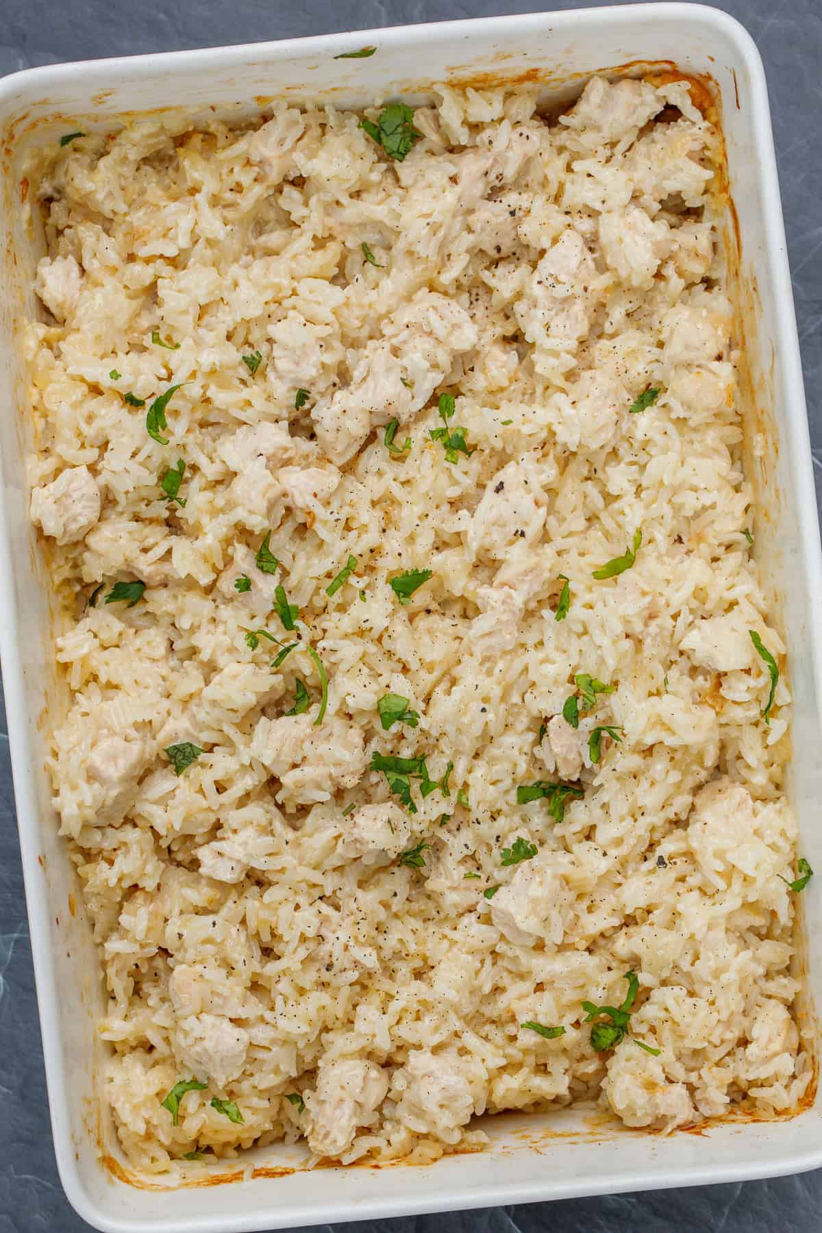 This classic chicken and rice casserole is the perfect traditional recipe. A casserole dish with creamy chicken and rice garnished with parsley.