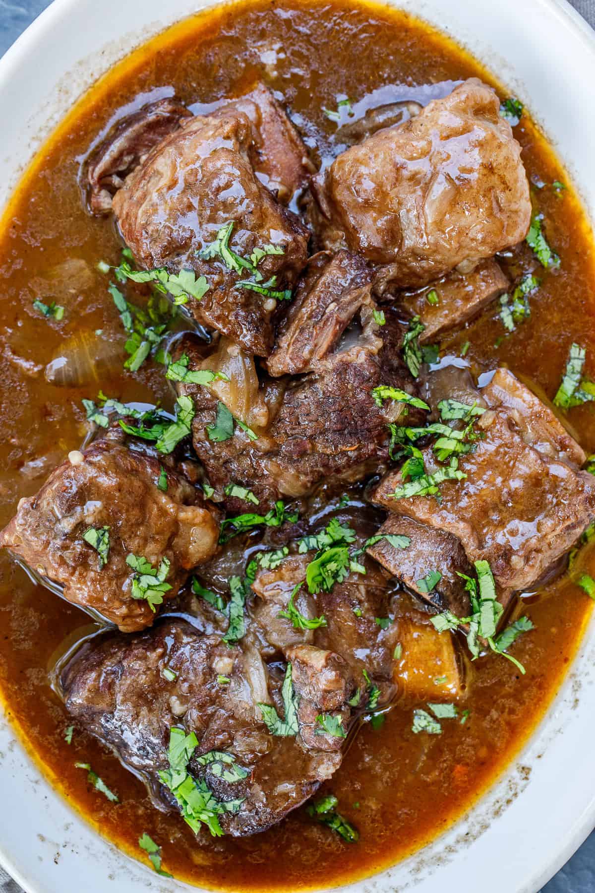 This recipe for slow cooker short ribs makes the most flavorful and delicious comfort meal. Juicy meat cooked to a tender perfection. A casserole dish with the juicy beef short ribs braised in wine.