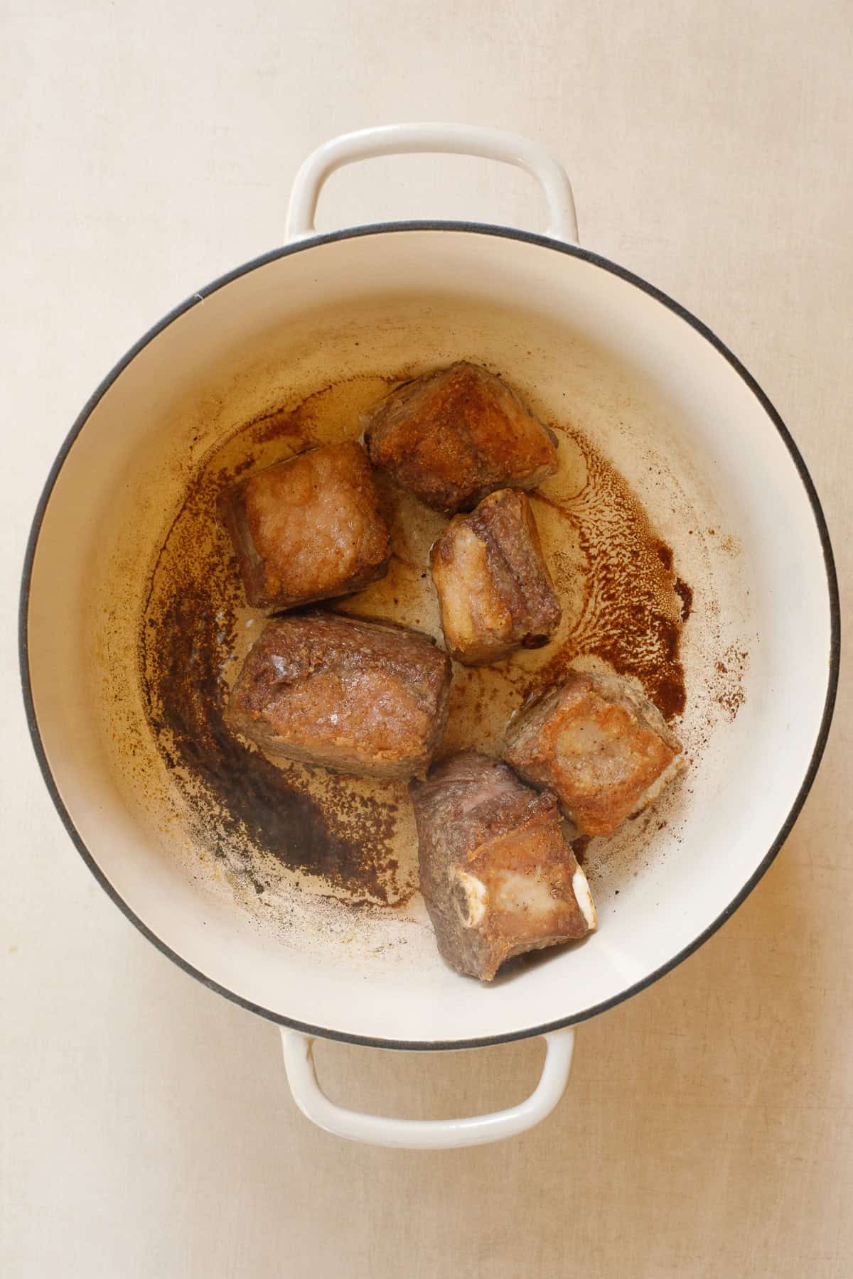 This easy slow cooker short ribs recipe makes a star meal with just a few simple ingredients. The short ribs being seared in a dutch oven.