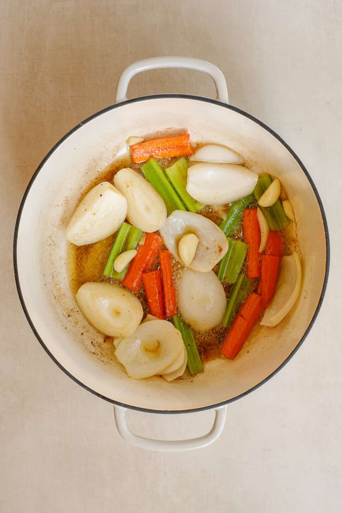 Our slow cooker short ribs recipe makes the perfect elevated meal with little to no effort. A dutch oven with the vegetables cooking down.