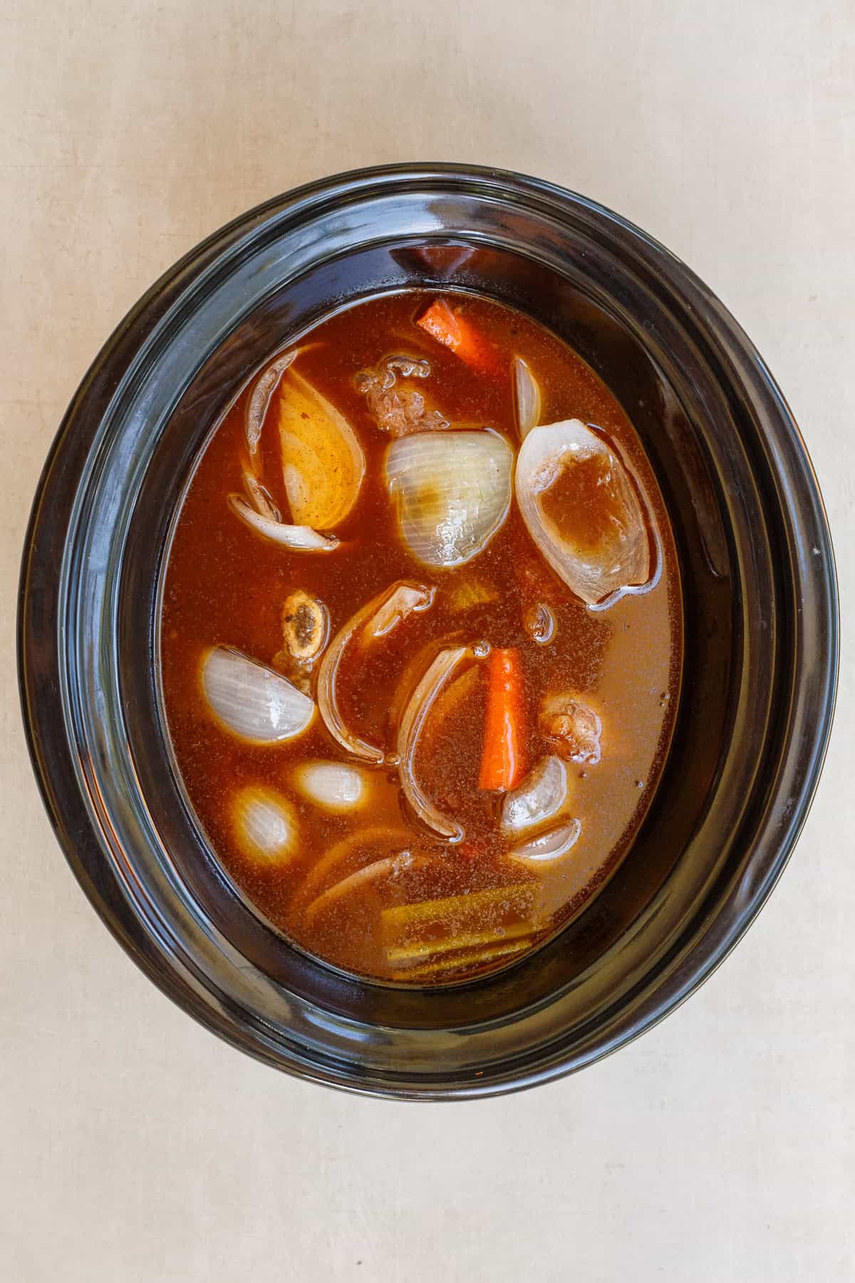 The slow cooker makes the best comfort meal from scratch: beef short ribs. The slow cooker with the meat, veggies, and broht.