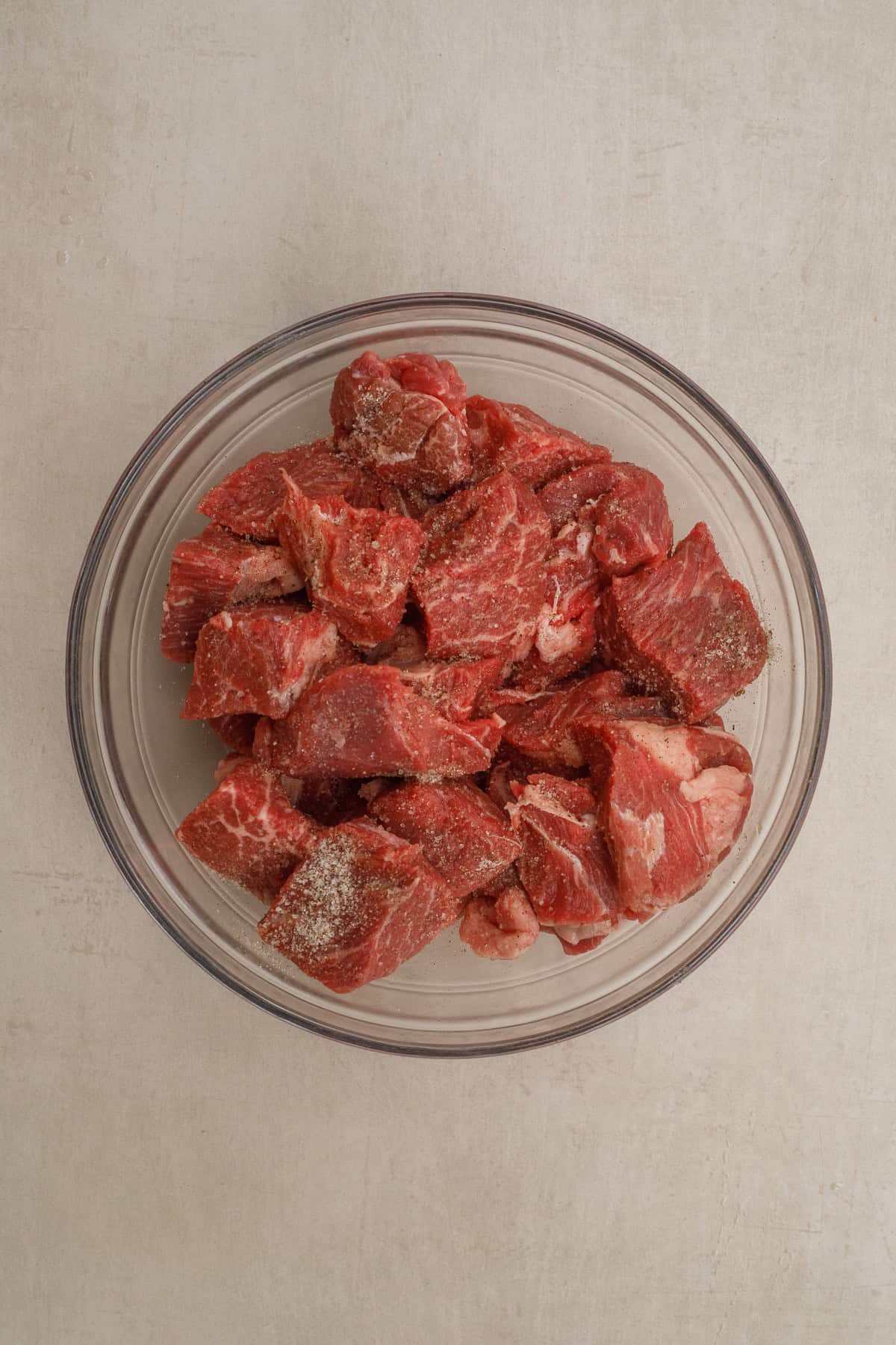 This easy crockpot beef stew recipe makes the perfect comfort meal. A glass bowl with cubed and prepped meat.