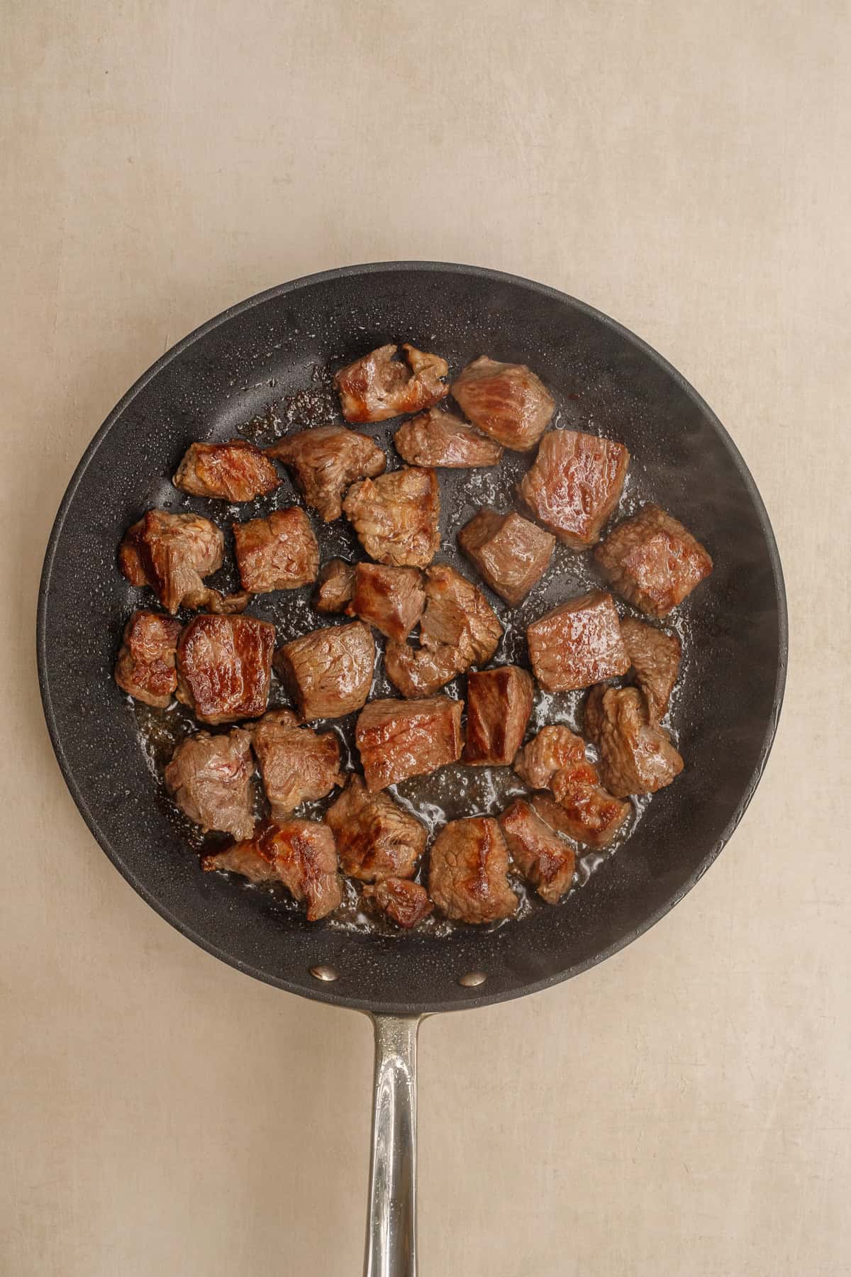 Beef chunks are slow cooked in a rich broth to give you the most tender beef stew. The seared beef in a pan.