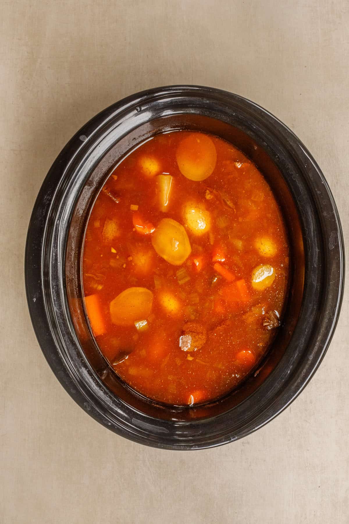 This crockpot beef stew is the perfect comfort meal that comes together in the slow cooker. A crockpot with the beef stew topped with broth.