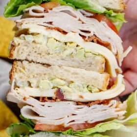Two stacked sandwiches, topped high with turkey, cheese, and veggies.