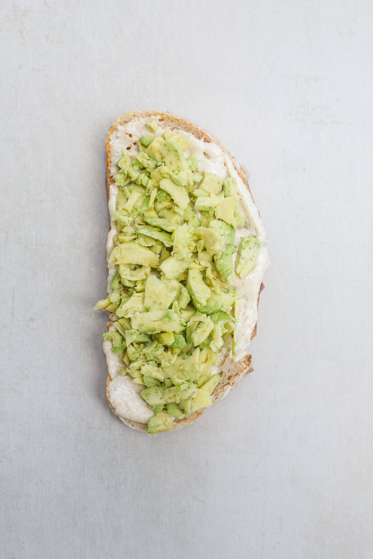 This homemade turkey sandwich is made so delicious with fresh avocado, a variety of meats, and bursting tomatoes. The bread slice, topped with smashed avocado.