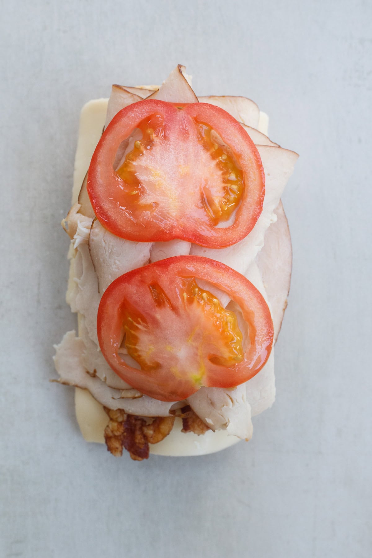 Our easy turkey sandwich recipe is the perfect lunch to recreate. The sandwich with tomatoes on top.