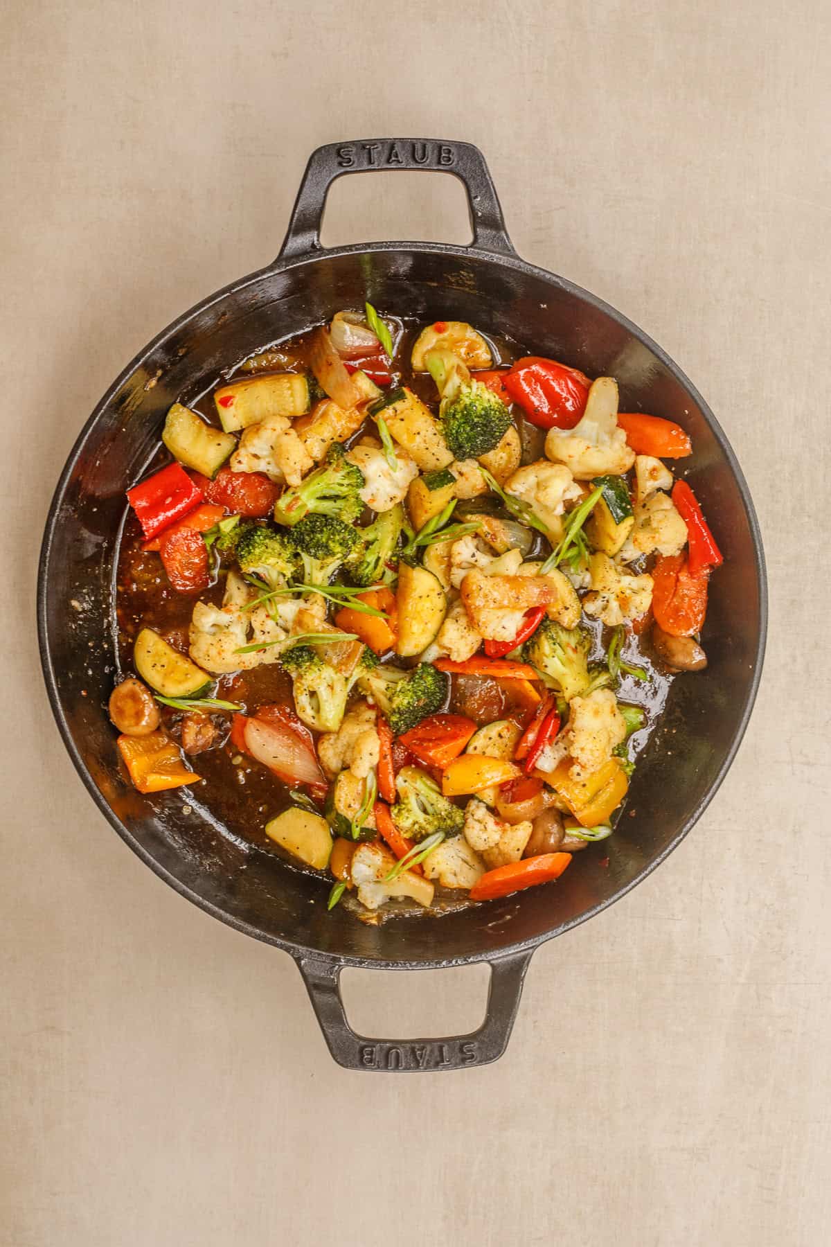 You will love these thai chili vegetables recipe. The veggies are fried to a tender finish and are cooked in the sweet and spicy sauce. A cast iron pan with the sauteed vegetables in thai chili sauce.