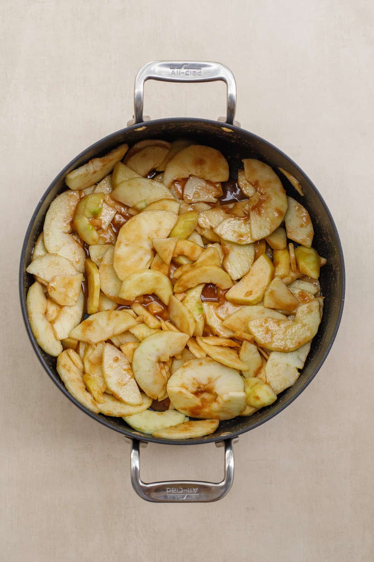 A classic dutch apple pie is the perfect holiday dessert to make from scratch. A pan with the apple pie filling sauce and fresh apples.