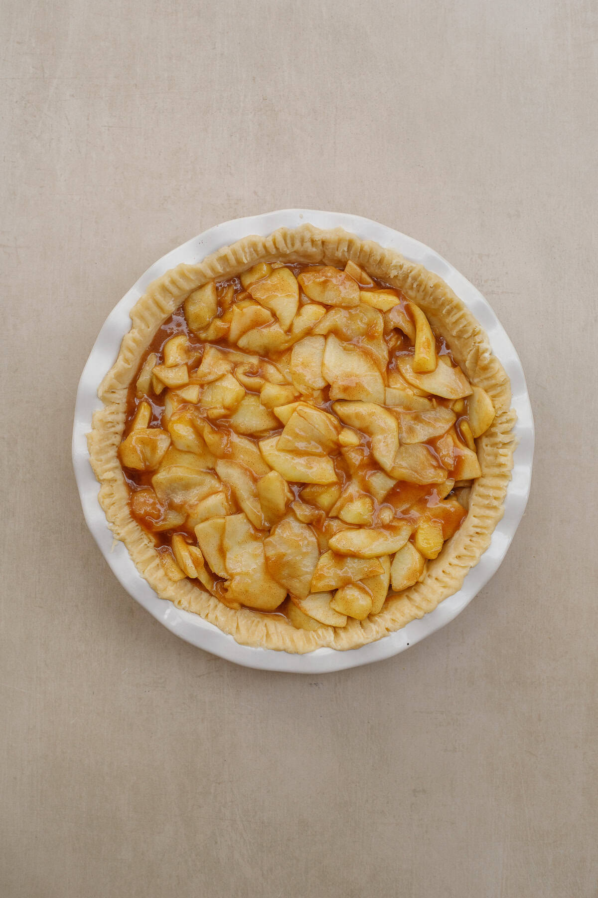 Our classic apple pie recipe is the perfect holiday dessert to make from scratch. A pie dish with the apple pie crust and filling.