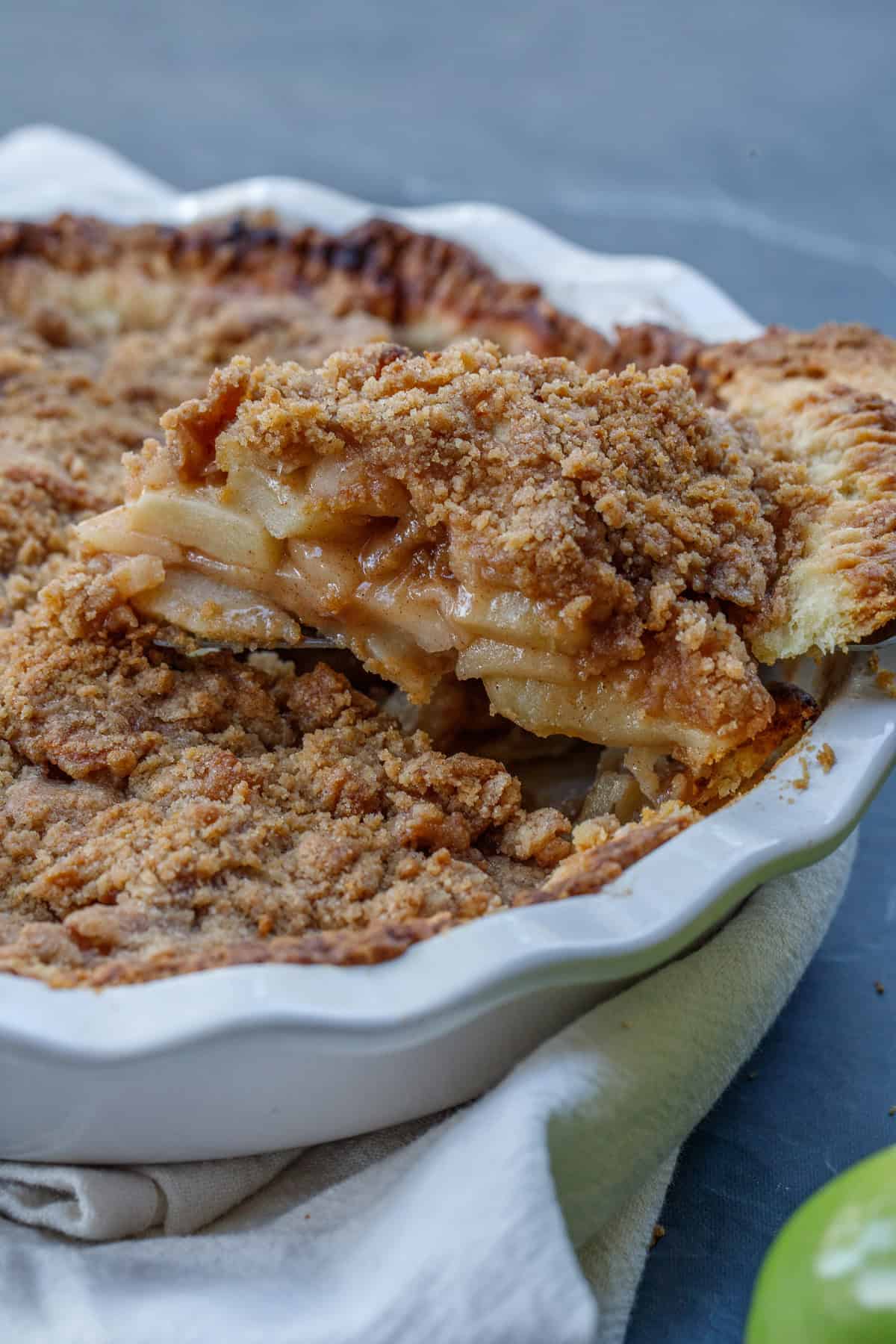 A slice of dutch apple pie with ice cream makes the best holiday dessert from scratch. A slice of dutch apple pie out of a pie dihs.