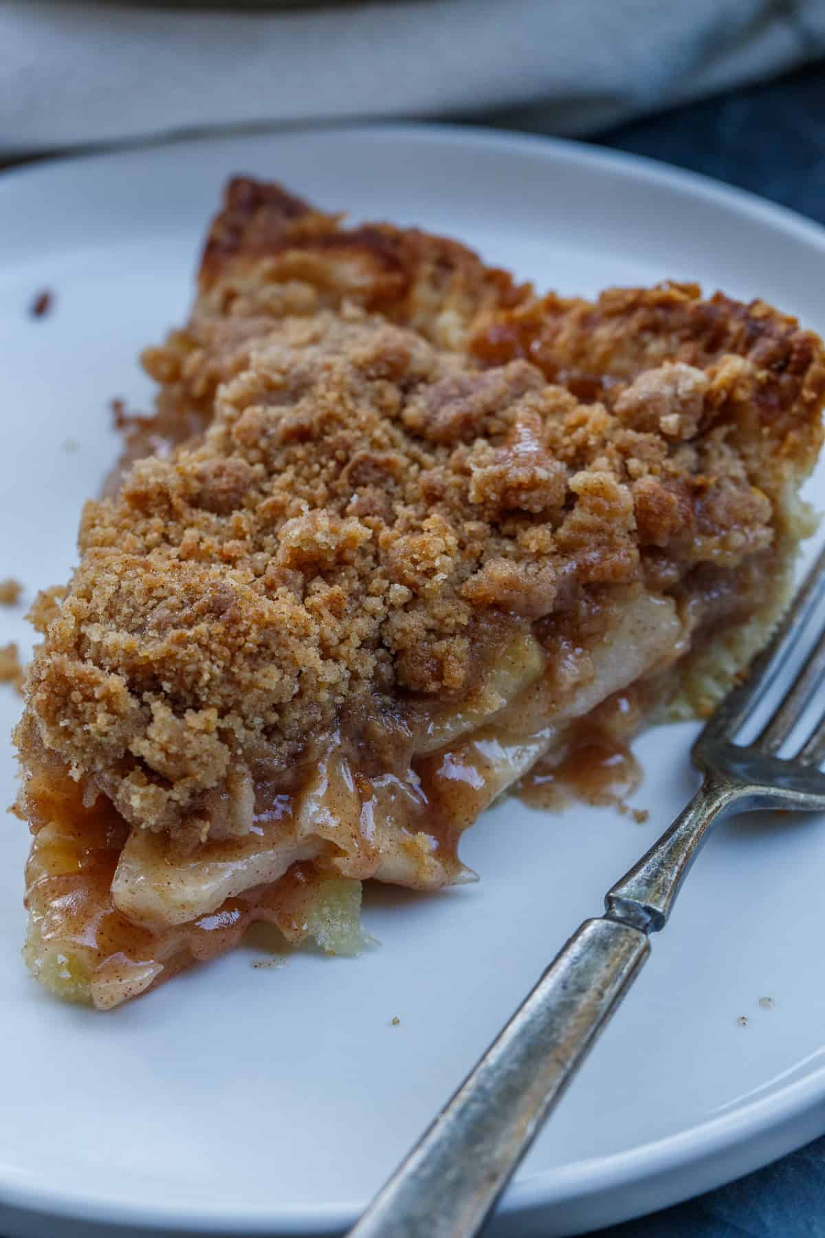 This dutch apple pie recipe is so simple to make and will be the start dessert at your next thanksgiving. A plate of dutch apple pie with a crumb topping.