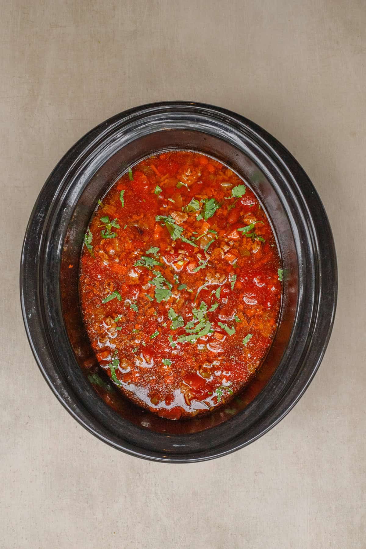 An easy chili in the crockpot makes the perfect comfort meal. A slow cooker with the cooked chili.