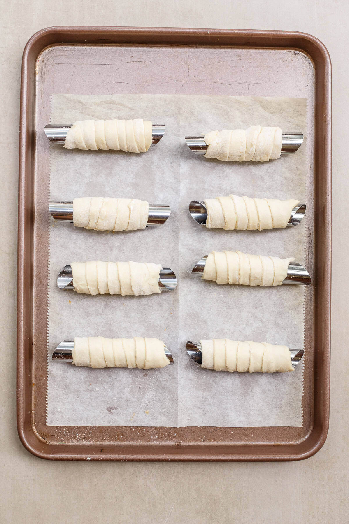 Crispy puff pastry is filled with a rich pistachio buttercream and coated in melted chocolate. The puff pastry strip wrapped around the molds.