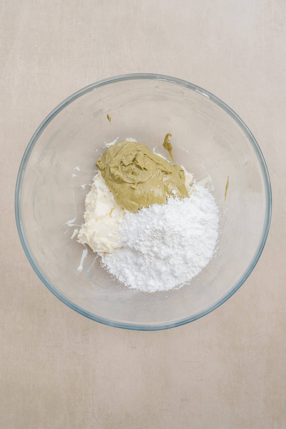 These dubai chocolate horns are made extra delicious with a homemade pistachio buttercream. A glass bowl with cream cheese, pistachio, and powdered sugar.