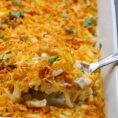 A casserole dish with a spoonful of cheesy hashbrown.