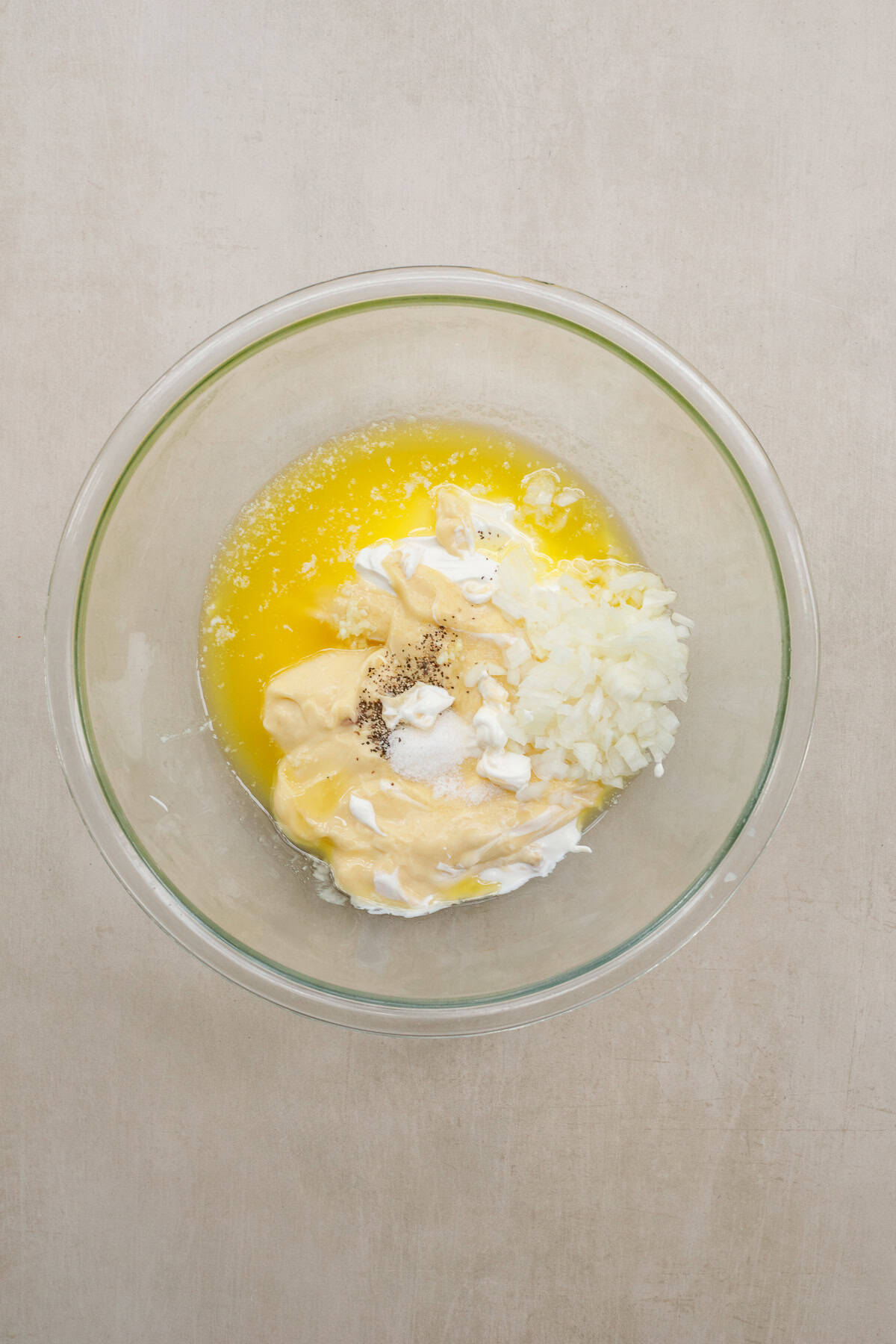 Our homemade hash brown casserole is made extra delicious with loads of cheese and crispy corn flakes. A glass bowl with the hash brown casserole mixture.