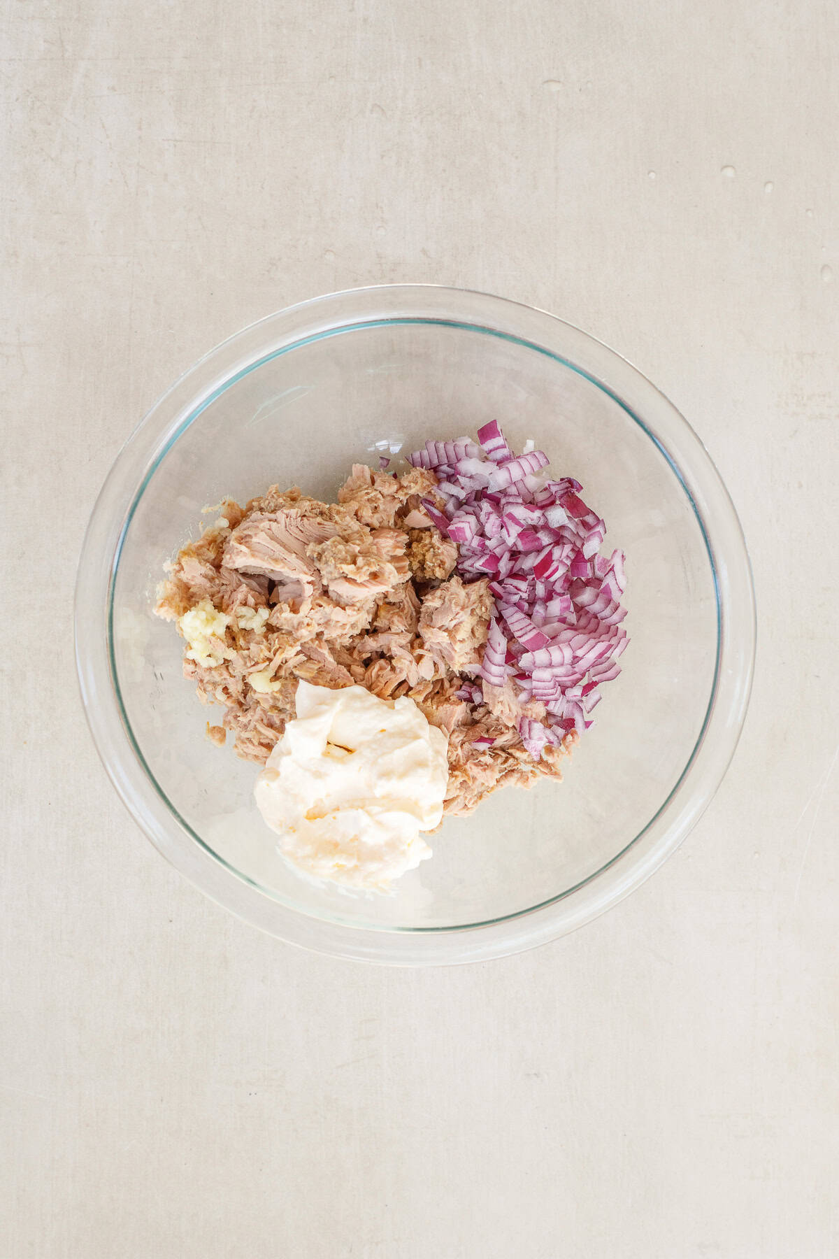 A simple tuna melt sandwich recipe takes simple ingredients and makes the perfect tasty lunch. A glass bowl with all of the tuna melt ingredients.