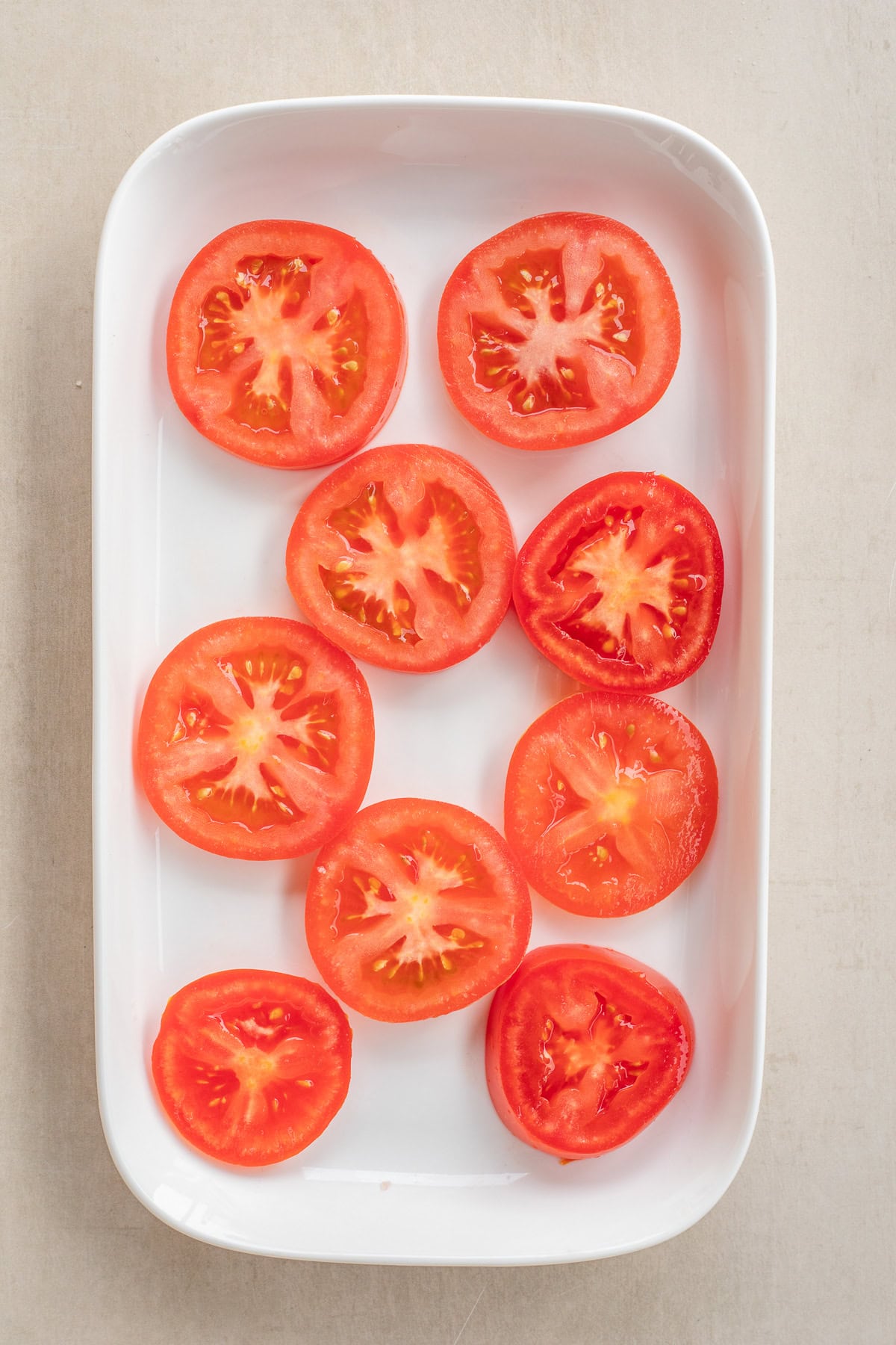A simple tomato and cheese appetizer that tastes great and is easy to make A casserole dish with the sliced tomatoes laid out.