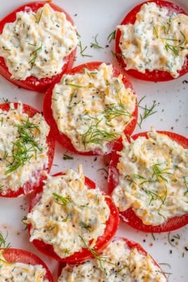 A plate of fresh tomatoes, topped with a cheesy garlic spread.