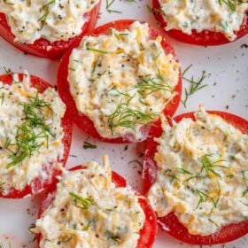 A plate of fresh tomatoes, topped with a cheesy garlic spread.