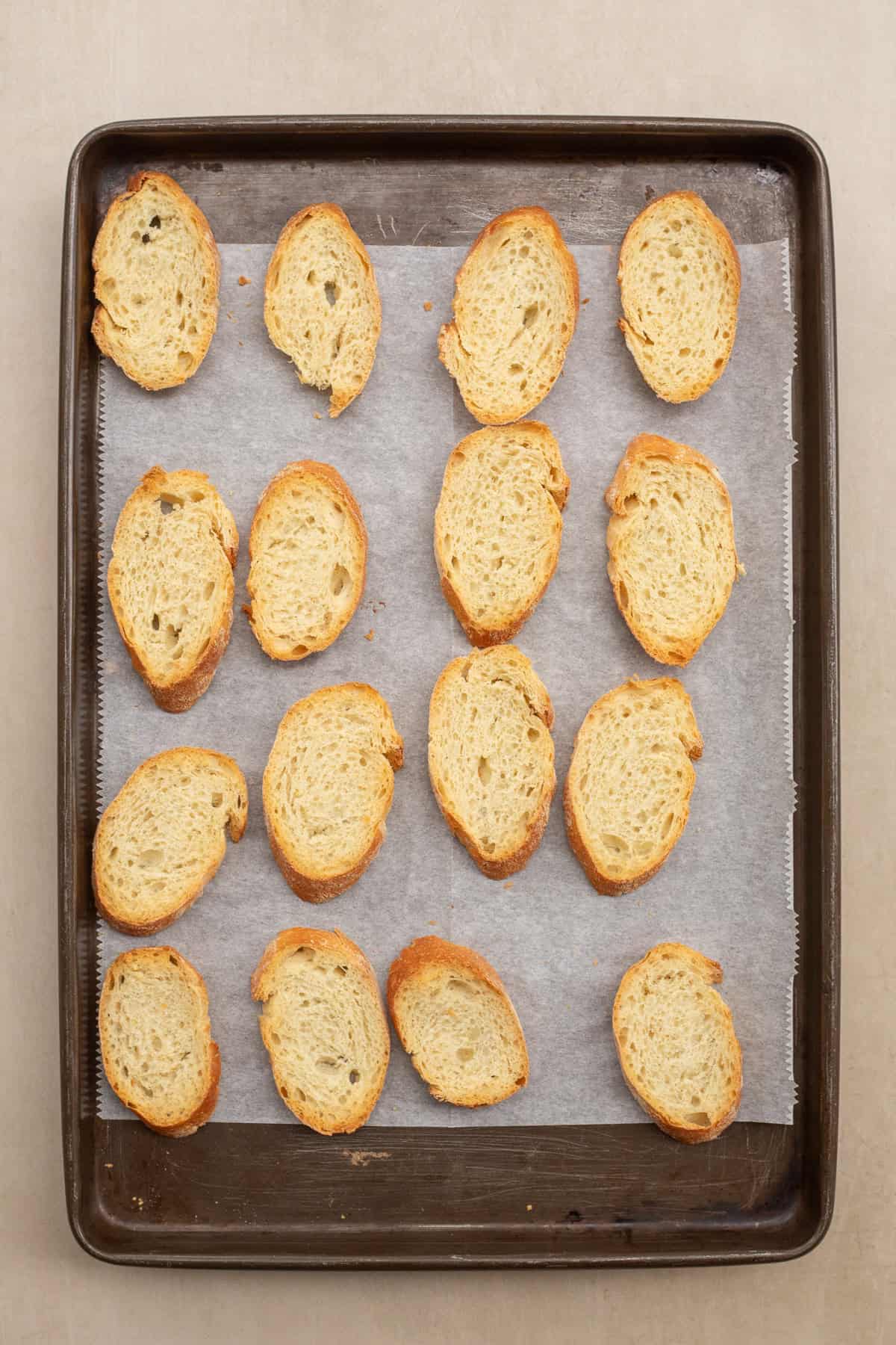 Easy pesto and tomato canapes make the best finger food. A sheet pan with the arranged bread slices.