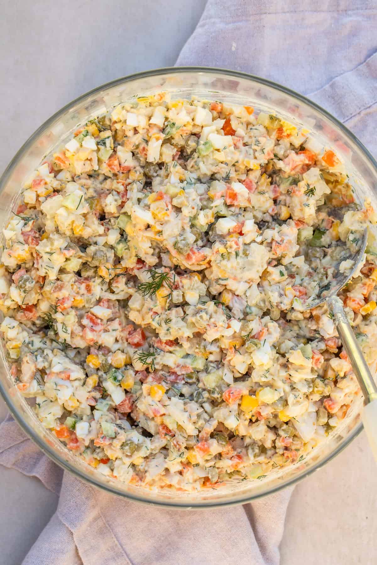 An easy egg and potato salad, known as a chicken olivye. Creamy chicken olivye in a salad bowl.