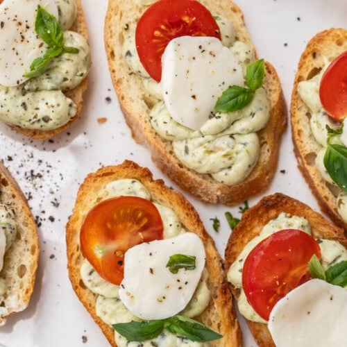 Slices of bread topped with a pesto cream, mozzarella, and fresh tomatoes.