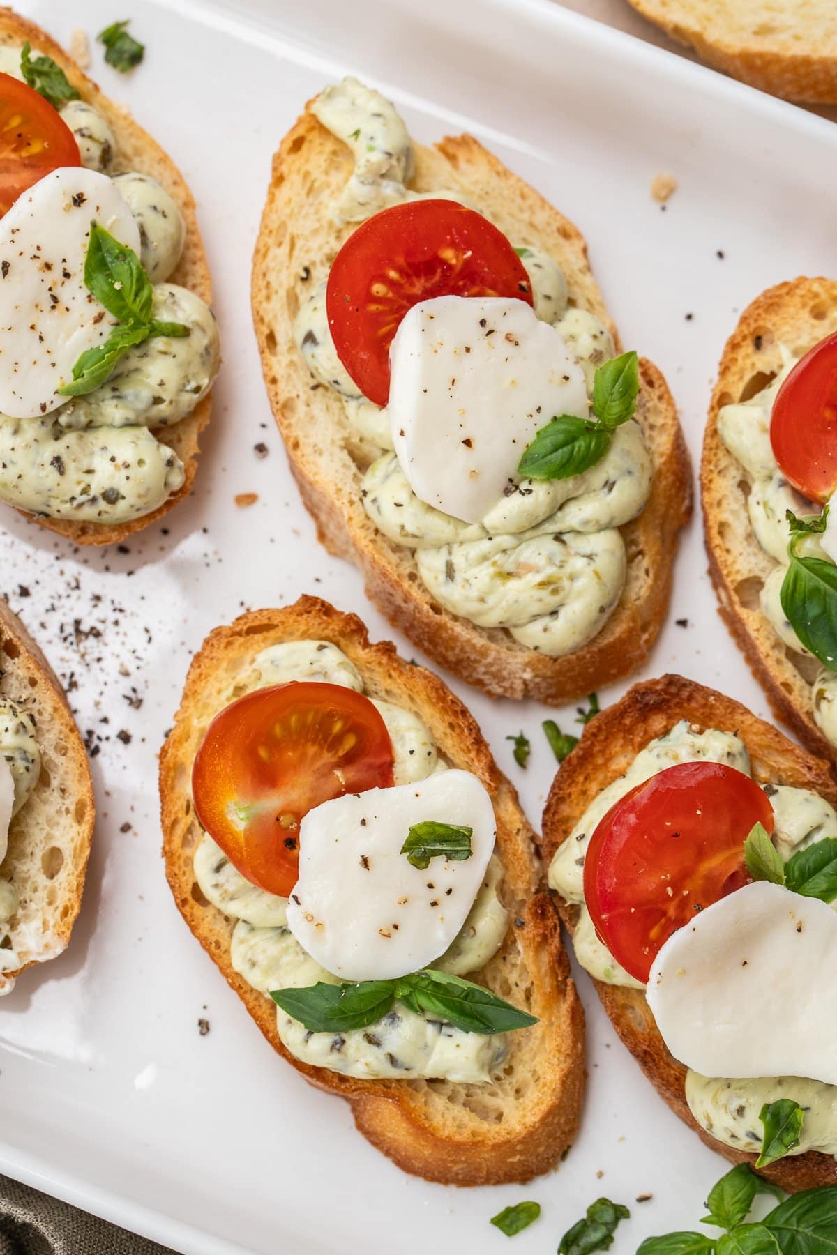 These pesto and tomato canapes make the perfect finger food in less than 20 minutes. Slices of bread topped with a pesto cream, mozzarella, and fresh tomatoes.
