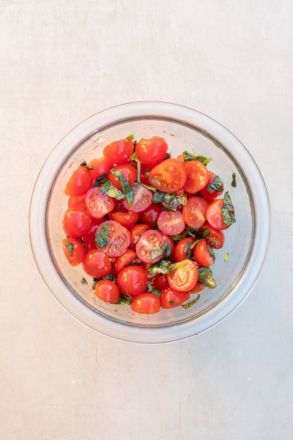 Bruschetta cheese dip is the perfect classy appetizer that cooks in less than 20 minutes. A glass bowl with the bruschetta topping ingredients.