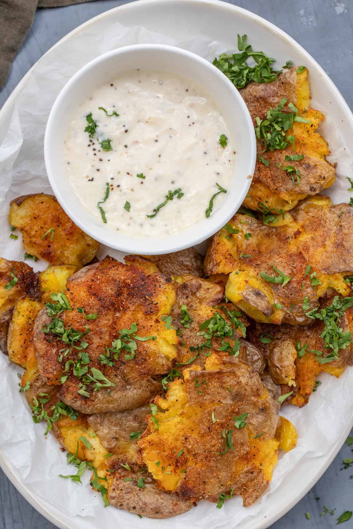 Classic smashed potatoes made crispy in the oven. A plate of smashed potatoes and a side of garlic aioli.