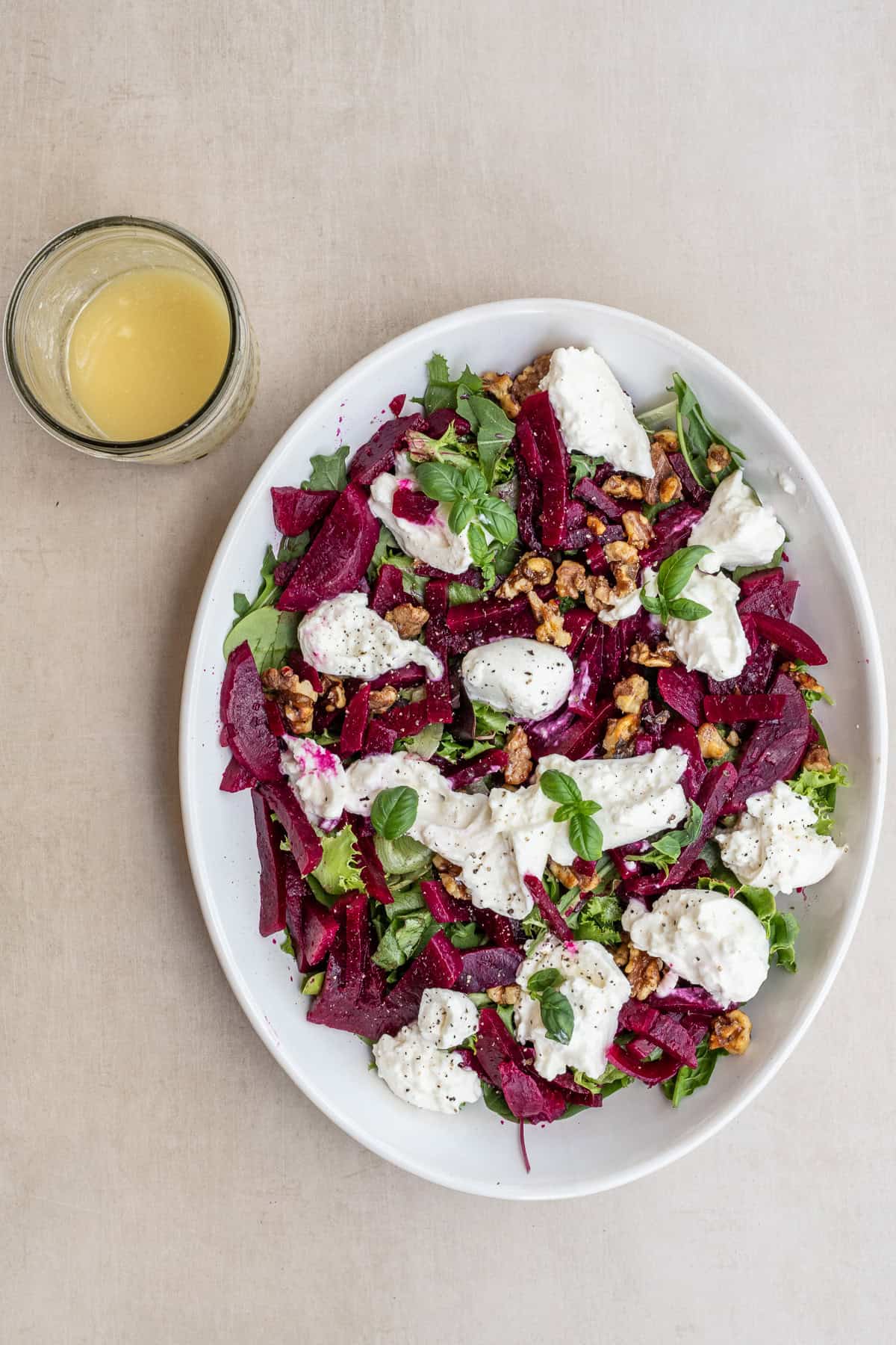 Easy Beet Salad Recipe (Fresh, Healthy & Flavorful) Beet and goat cheese salad with walnuts, greens, and vinaigrette on a white platter.